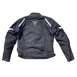 May include: Black motorcycle jacket with white accents and a white logo on the back. The jacket has a collar, long sleeves, and a waist adjustment. The brand name is printed on the lower back.