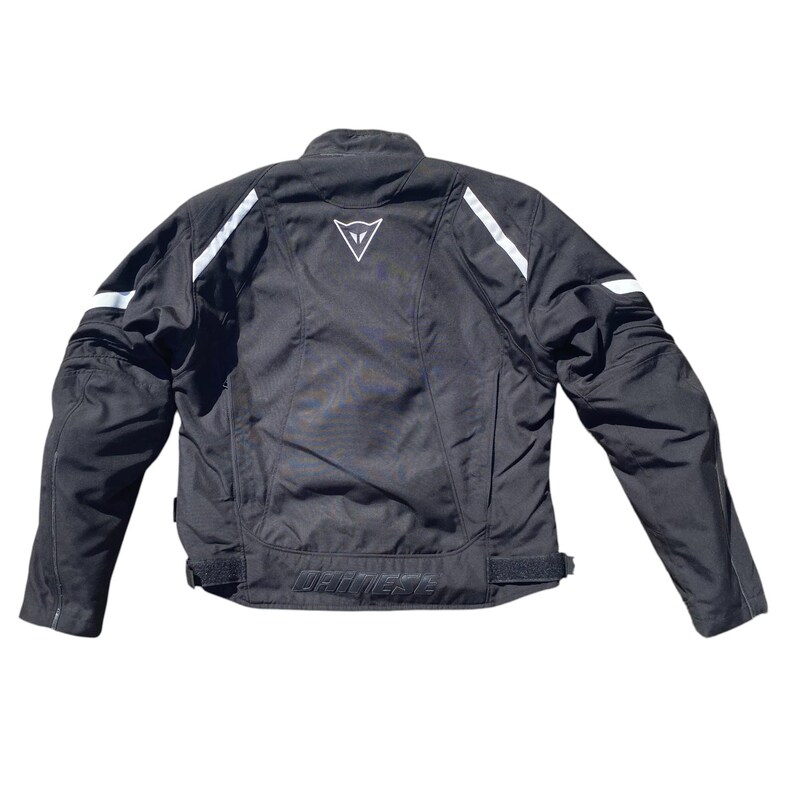 May include: Black motorcycle jacket with white accents and a white logo on the back. The jacket has a collar, long sleeves, and a waist adjustment. The brand name is printed on the lower back.