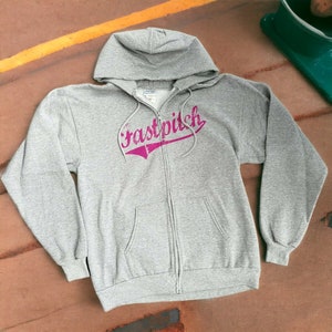 May include: Gray zippered hoodie with a pink "fastpitch" graphic on the front.