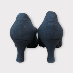May include: Pair of black fabric heels with a textured appearance. The heels have a curved design and a rounded toe. The shoes are set against a white background.