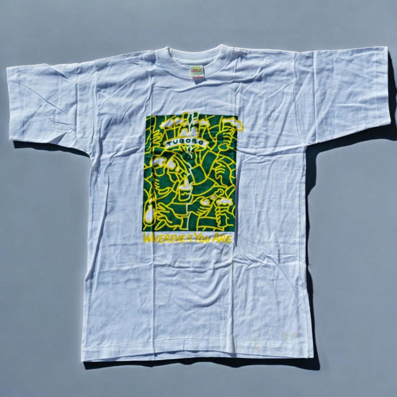 May include: White t-shirt featuring a green and yellow graphic print of people holding up beer bottles. The graphic includes the text "Tuborg" and "Wherever you are".