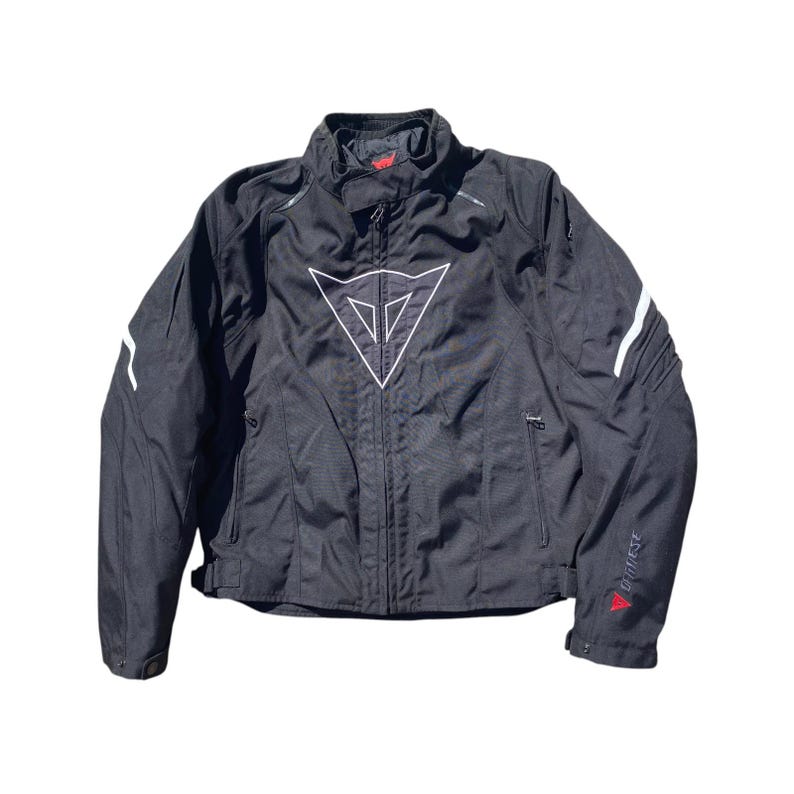 May include: Black motorcycle jacket with white accents and a large white logo on the chest. The jacket has a zippered front, pockets, and white stripes on the sleeves. The brand name is visible on the sleeve.