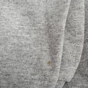 May include: A close-up of a gray sweatshirt with a small brown stain.