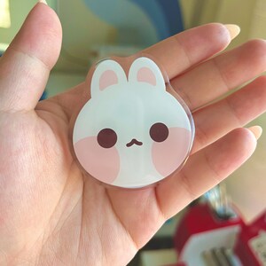 May include: A white and pink resin bunny charm with a cute cartoon face. The charm has large, round eyes and a small, pink nose.