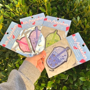 May include: Three air freshener car hang tags featuring a boba tea design. The tags are in a clear plastic bag. The boba tea designs are purple, green, and blue. The text on the tags reads "air freshener" and includes the Etsy shop name "Curry Senpai".