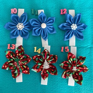 May include: Ten handmade fabric hair bows with a Christmas theme. The bows are in red, white, and blue with snowflake and Christmas tree designs. The bows are numbered 10 through 15.