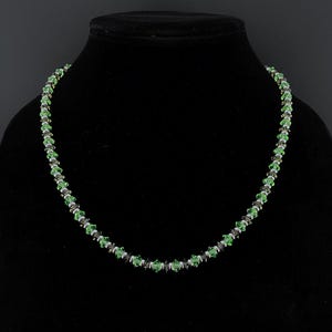 May include: A white ceramic mug with a black handle and the text "But First, Coffee" in a bold, black font. The mug is set against a blurred background, suggesting a cozy setting.