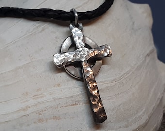 May include: A silver Celtic cross pendant with a hammered finish, hanging on a black leather cord. The cross is a traditional Irish design with a circle around the center.