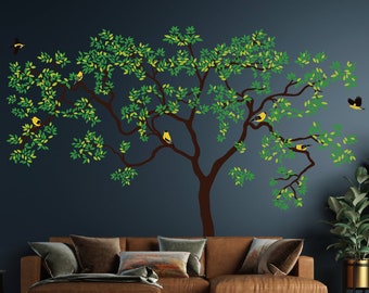 May include: A wall decal featuring a large tree with green leaves and brown branches.  The tree has several yellow birds perched on the branches. The decal is on a dark blue wall.