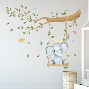 Peut inclure: Adhésif mural fantaisiste représentant un éléphant bleu clair sur une balançoire en bois suspendue à une branche d'arbre. La scène comprend des feuilles vertes, des oiseaux colorés, des papillons et des notes de musique, pour une chambre d'enfant.