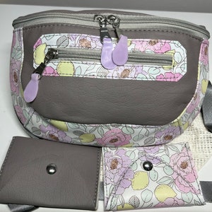 May include: A gray and white floral fanny pack with a zippered pocket and a detachable pouch. The fanny pack has a gray strap and a white mesh pouch.