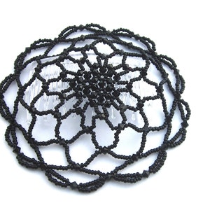 May include: Black beaded hair comb with a floral design. The comb is made of black beads and has a clear plastic comb attached to the back.