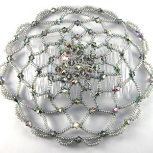 Può includere: Un pettine per capelli in perle argentate con cristalli iridescenti. Il pettine è progettato in forma circolare con un motivo delicato e intricato.