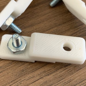 Puede incluir: Tres soportes de pl&aacute;stico blanco con un tornillo y una tuerca unidos a cada uno. Los soportes tienen un peque&ntilde;o agujero en el centro.