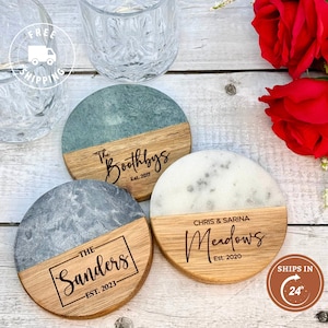 May include: Three round coasters with a marble top and a wooden base. The coasters are personalized with names and the year established. The coasters are on a wooden surface.