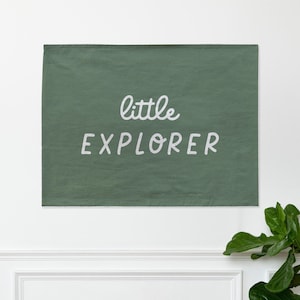 May include: A green fabric wall banner with white text that reads "little EXPLORER".