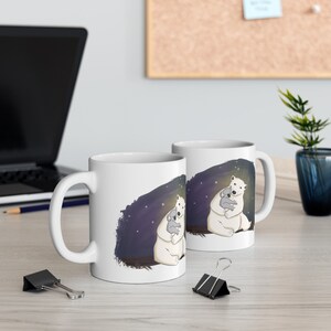 Pu&ograve; includere: Due tazze in ceramica bianca con un design di un orso polare che abbraccia un koala su uno sfondo di notte stellata blu scuro.