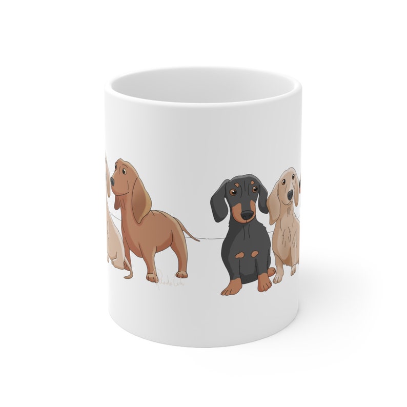 May include: White ceramic mug with a cartoon illustration of four dachshund dogs. The dogs are brown, black, and cream colored. The dogs are all looking at the viewer.