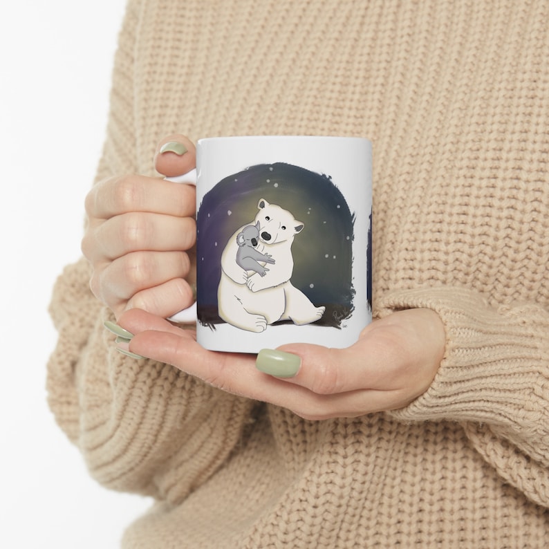 Pu&ograve; includere: Tazza in ceramica bianca con un'immagine di un orso polare che abbraccia un koala su uno sfondo blu scuro con stelle bianche.