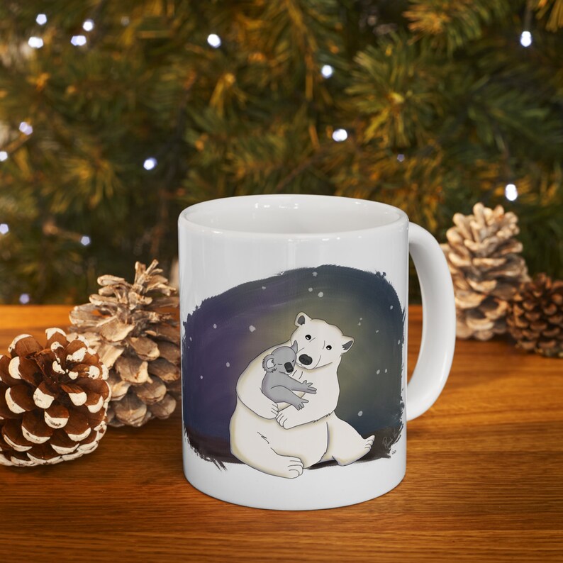 Pu&ograve; includere: Tazza in ceramica bianca con un'immagine di un orso polare che abbraccia un koala. Lo sfondo &egrave; blu scuro con stelle bianche.