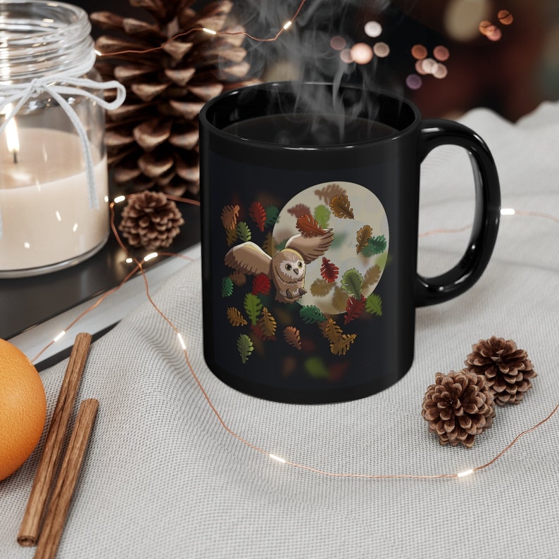 Pu&ograve; includere: Tazza da caff&egrave; nera con un gufo bianco che vola attraverso una foresta illuminata dalla luna con foglie autunnali. Il gufo ha piume marroni e bianche e guarda a sinistra. La tazza ha un manico nero.