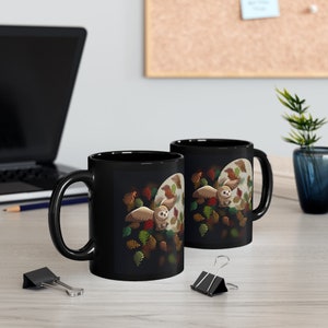 Pu&ograve; includere: Due tazze in ceramica nera con un design di un gufo che vola tra le foglie autunnali. Il gufo &egrave; marrone e bianco con un becco giallo. Le foglie sono in tonalit&agrave; di marrone, arancione e giallo.