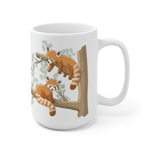May include: White ceramic mug with a red panda design. Two red pandas are perched on a tree branch with green leaves. The mug has a white handle.