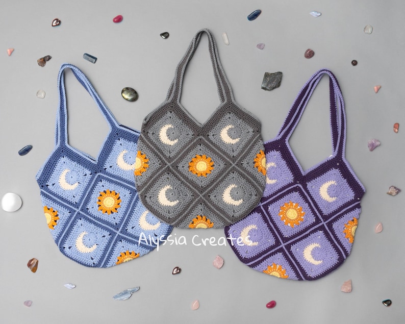 May include: Three crocheted tote bags with a sun and moon design. The bags are in blue, purple, and gray.