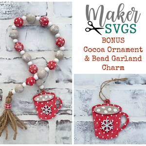 May include: A red and white cocoa mug ornament with a snowflake and marshmallows, hanging from a brown twine string. A red and white bead garland with a brown tassel hangs from a white brick wall. The text "Maker SVGs BONUS Cocoa Ornament & Bead Garland Charm" is displayed in the image.