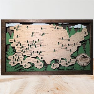 May include: A wooden map of the United States with state names and tree icons. The map is framed in a dark brown wood and features green trees around the edges. The Garcia Family name is on the bottom right.