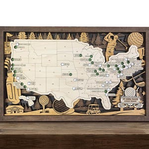 May include: Wooden golf course tracker map of the United States, featuring a detailed laser-cut design. The map includes golf-themed illustrations, green markers, and the text "Top Course Tracker". The frame is dark brown.