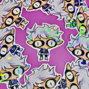 May include: A collection of stickers featuring a cartoon character with white hair, large oval eyes, and a small black and green outfit. The stickers have a holographic, iridescent finish, and are arranged on a purple background.
