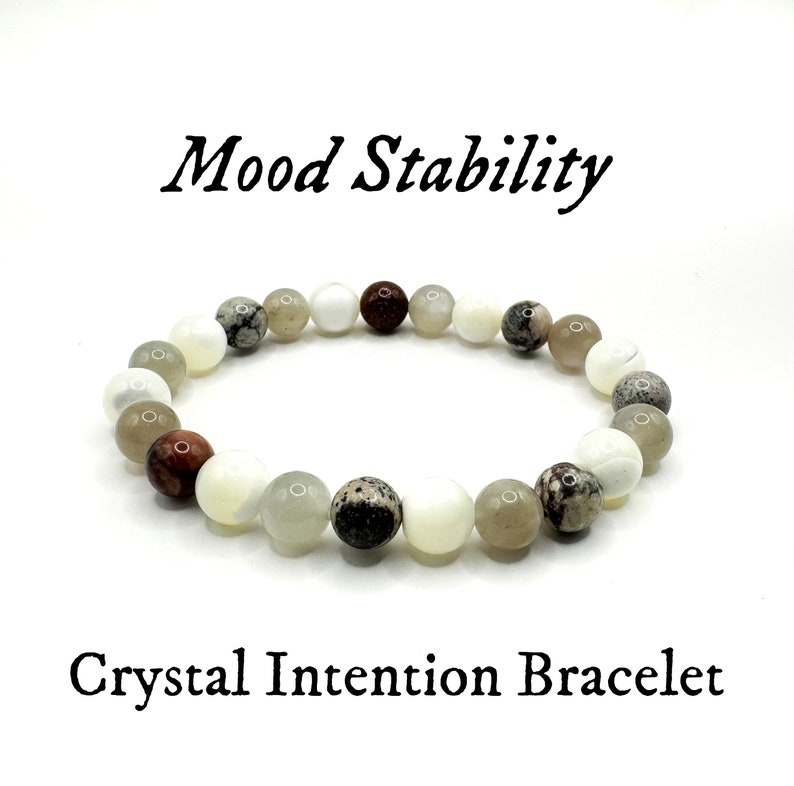 May include: Mood Stability Crystal Intention Bracelet with white, brown, and gray beads.