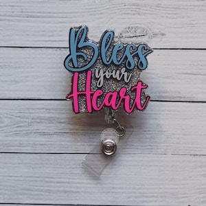 May include: A blue and pink glitter badge holder with the text "Bless your heart".