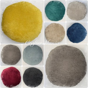 Könnte beinhalten: Zehn runde Samtkissen in verschiedenen Farben, darunter Gelb, Türkis, Beige, Blau, Grau, Hellblau, Braun, Rot und Schwarz. Die Kissen sind alle gleich groß und haben die gleiche Form und sind in einem Raster angeordnet.