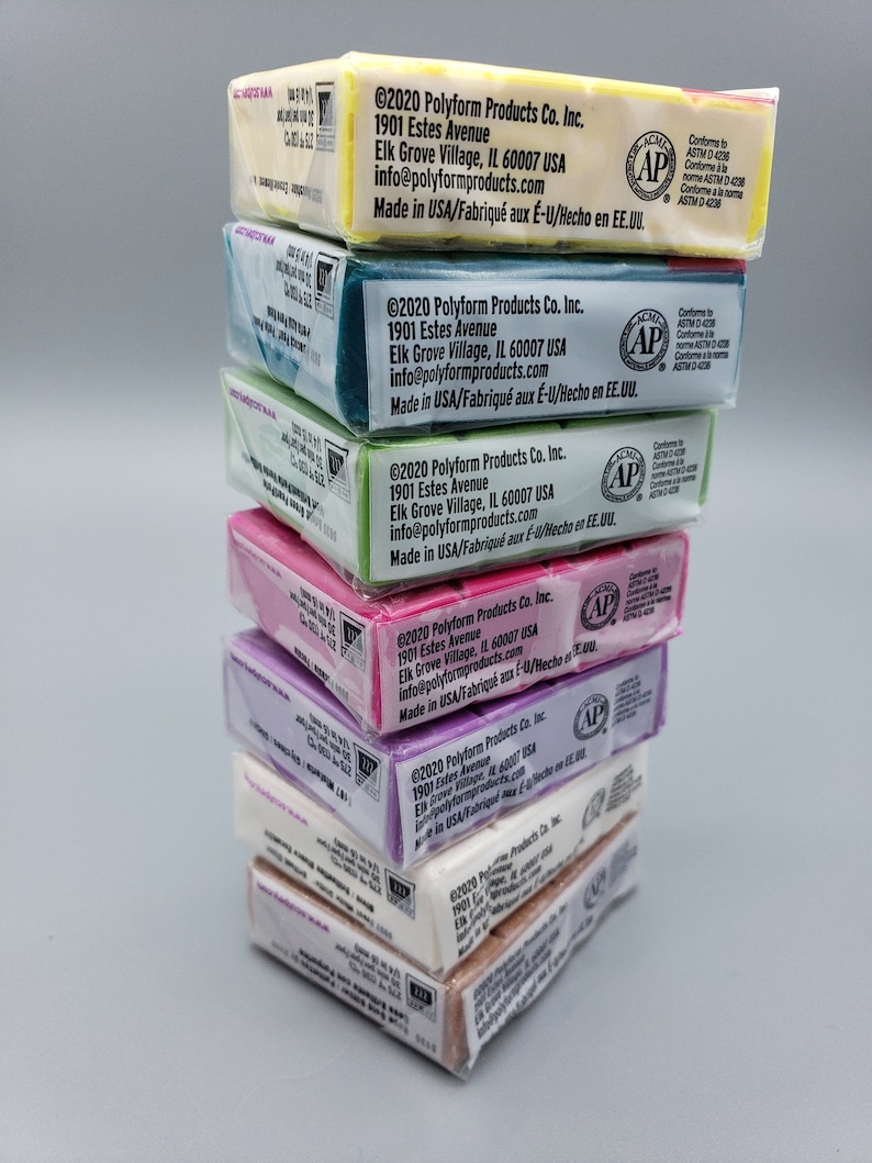 May include: A stack of polymer clay packages in various colours, including yellow, teal, green, pink, purple, white, and brown. Each package has printed text and the AP seal.