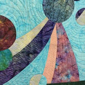 May include: A quilt with a blue background and colorful circular patterns. The quilt is made of different fabrics and has a variety of textures.