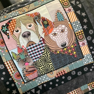 May include: A colorful patchwork quilt featuring three animal faces: a dog, a wolf, and a cat. The quilt is made of various fabrics with geometric patterns and is framed by a black border with white stars.