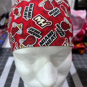Peut inclure: Un bonnet de chirurgien rouge avec un motif répété du logo et du texte des Miami Heat. Le bonnet est conçu pour s'adapter à la tête et est fait d'un matériau souple. Le logo des Miami Heat est répété sur le bonnet.