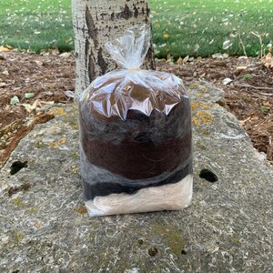 May include: A clear plastic bag filled with brown, black, and white wool roving. The roving is layered in a gradient pattern.