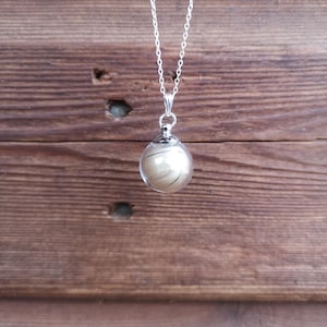 May include: A silver chain necklace with a clear glass orb pendant containing a lock of hair.