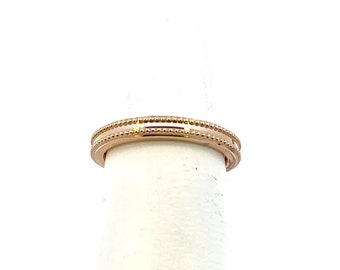 May include: A rose gold band ring with a textured design. The ring is on a white display stand.