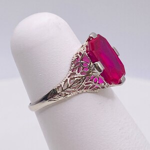 May include: A vintage ring with a large, faceted, pink gemstone set in a filigree design.