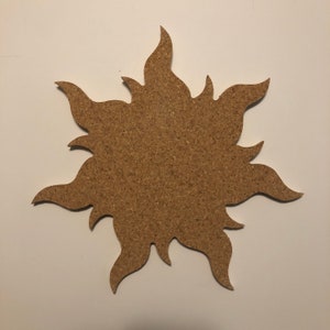 May include: A corkboard shaped like a sun with a brown, textured surface.