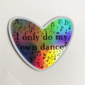 May include: A heart-shaped sticker with a rainbow iridescent background and black musical notes. The sticker has the text "I only do my own dance" in black.