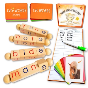 May include: An assortment of educational toys and games for children. Includes orange card decks labeled "CVCE WORDS" and "CVC WORDS", wooden word blocks, a "Magic Spin-E Blocks" box, a whiteboard, a marker, and flashcards with a horse illustration.