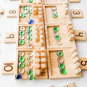You can use a variety of math counters and math manipulatives with our Counting Pegs Math Material. Here, the rectangular cut-out of our number panels allows you to use pebbles, beans, rice, & sand for more number practice!