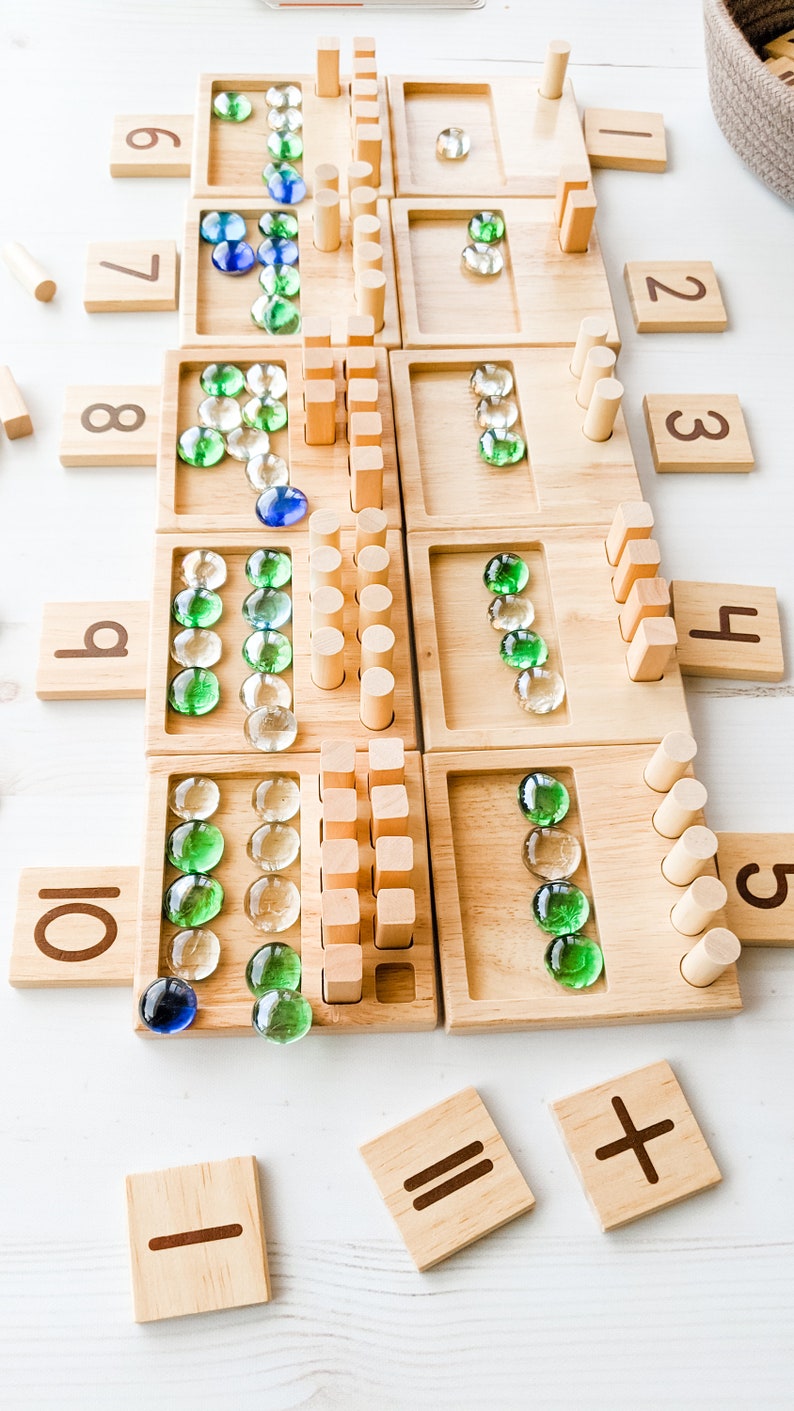 You can use a variety of math counters and math manipulatives with our Counting Pegs Math Material. Here, the rectangular cut-out of our number panels allows you to use pebbles, beans, rice, & sand for more number practice!
