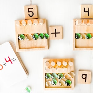 You can use a variety of math counters and math manipulatives with our Counting Pegs Math Material. Here, the rectangular cut-out of our number panels allows you to use pebbles, beans, rice, & sand for more number practice!