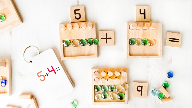 You can use a variety of math counters and math manipulatives with our Counting Pegs Math Material. Here, the rectangular cut-out of our number panels allows you to use pebbles, beans, rice, & sand for more number practice!